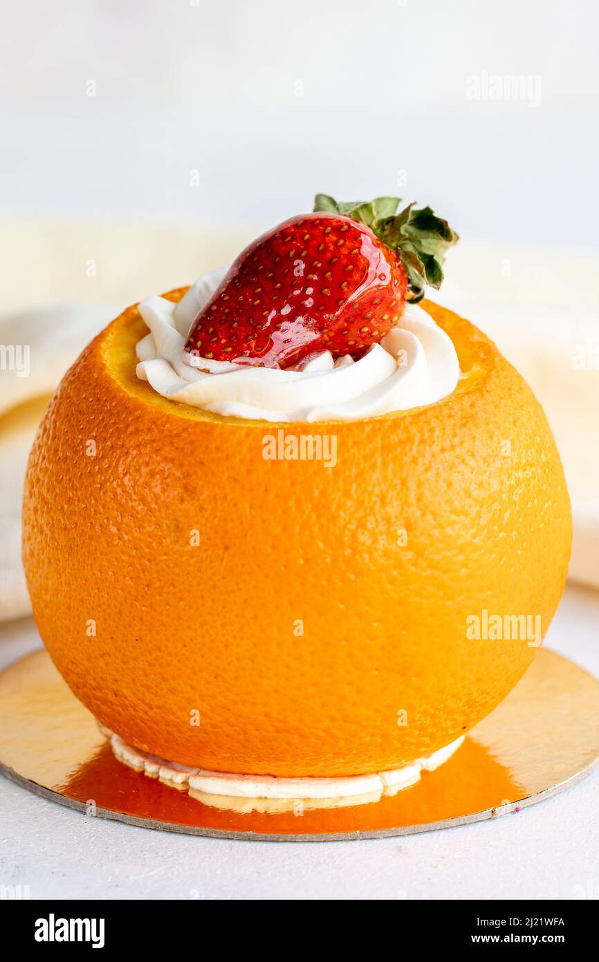 Torta all'arancia su sfondo bianco. Torta minuscola con crema e particelle d'arancia all'interno. Primo piano Foto Stock