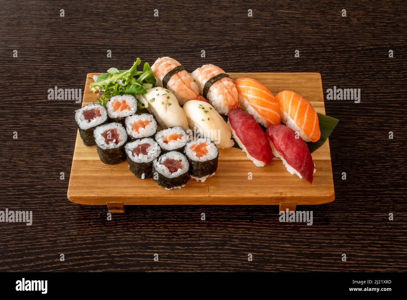 Vassoio di legno pieno di sushi assortiti con maki di tonno rosso e salmone norvegese con alghe nori, pesce farfalla e nigiri gamberi Foto Stock