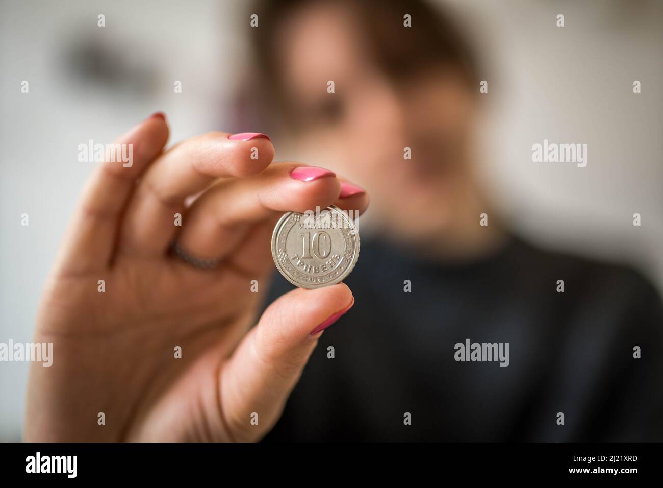 Foto Closeup della mano della donna che mostra il coin d'argento di 10 hryvnias ucraino. Concetto di economia dell'inflazione Foto Stock