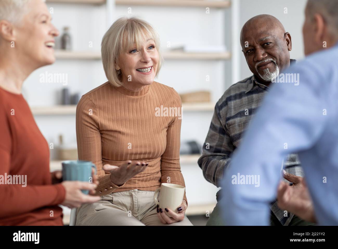 Ritratto di allegri pensionati seduti in cerchio, bere il tè Foto Stock