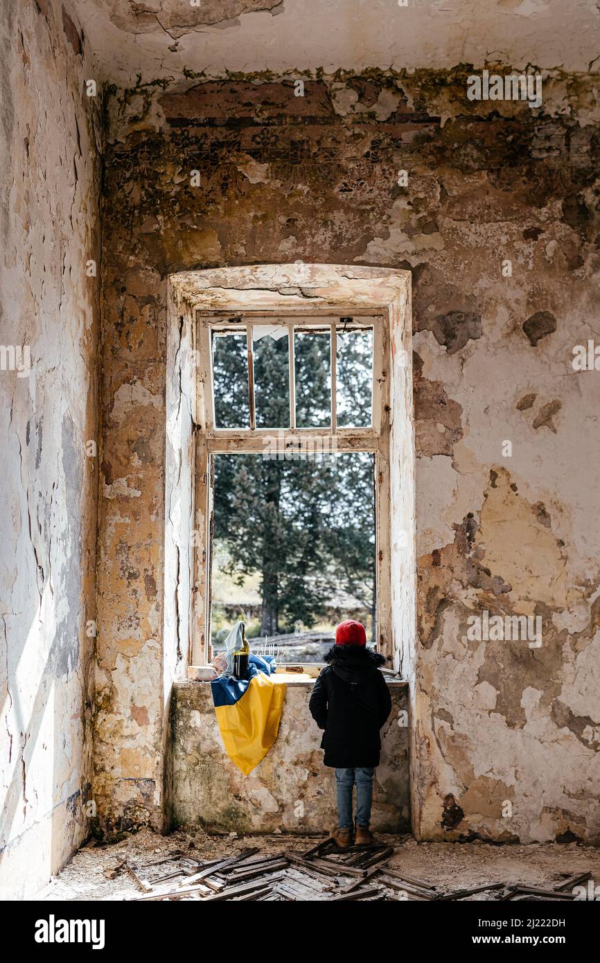 Little Boy in una guerra in rovina Casa in Ucraina bandiera Ucraina Foto Stock