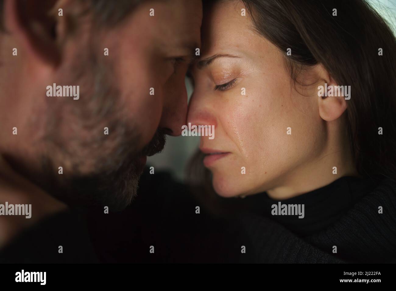 Primo piano di una donna che piange quando abbraccia il marito. Foto Stock