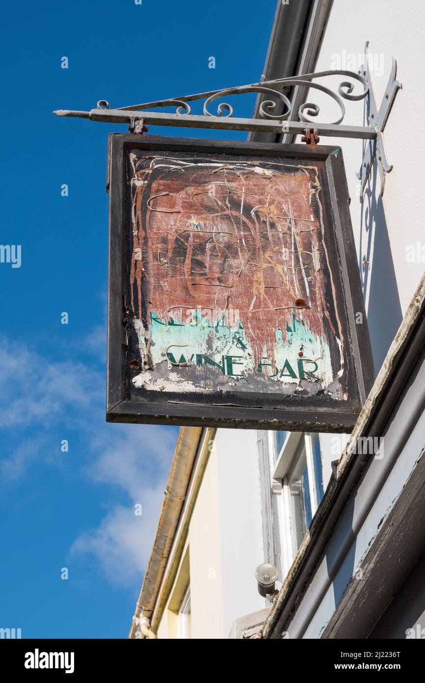 Vecchio cartello sbiadito con vernice da peeling sopra un wine bar a Modbury, Devon Foto Stock