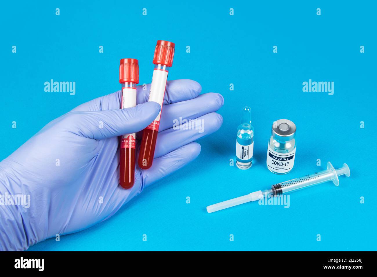 Mano di un medico che tiene un flacone di campione di sangue. Sfondo blu Foto Stock