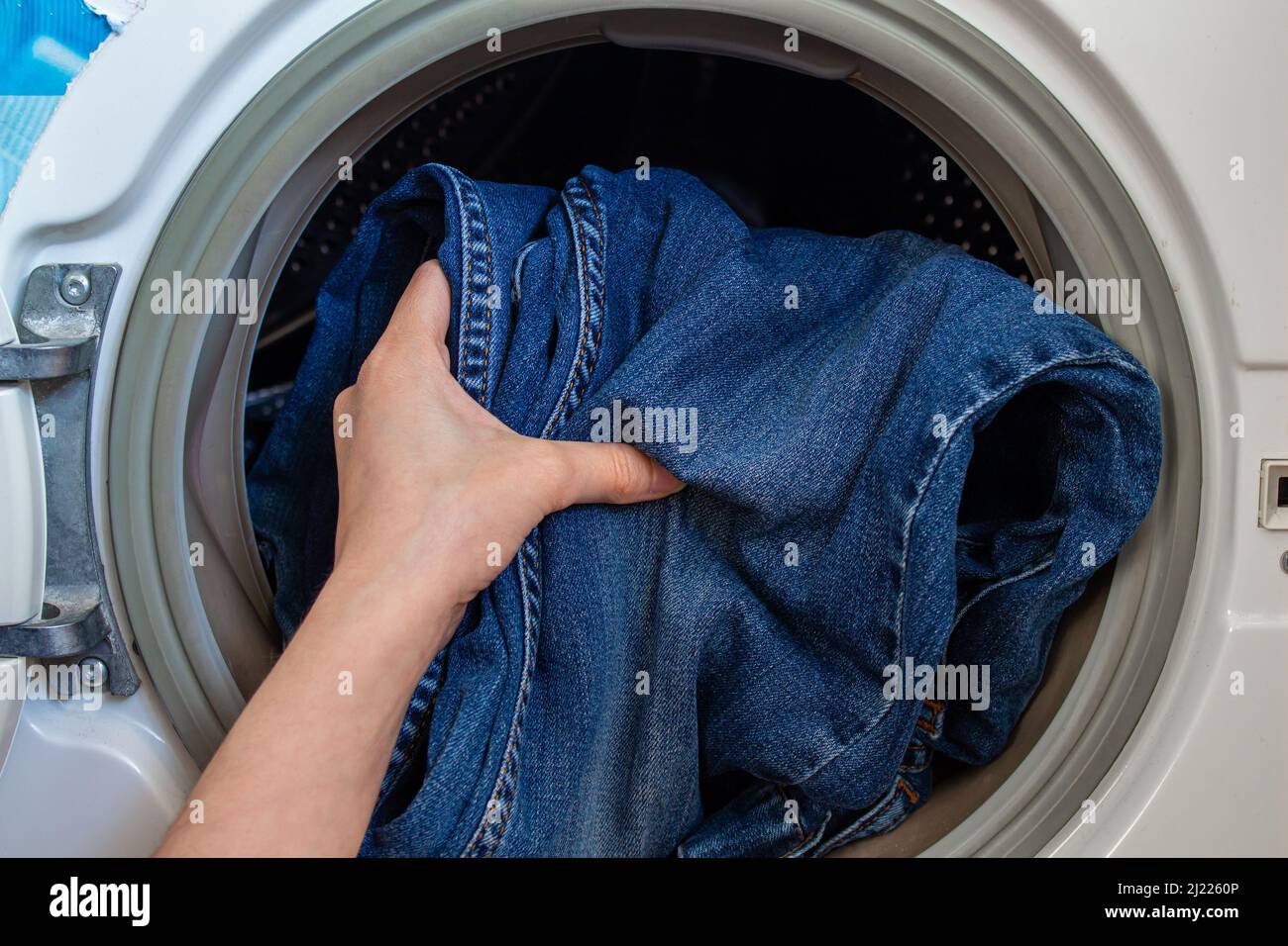 La donna è carica la lavatrice con vestiti sporchi. Foto Stock
