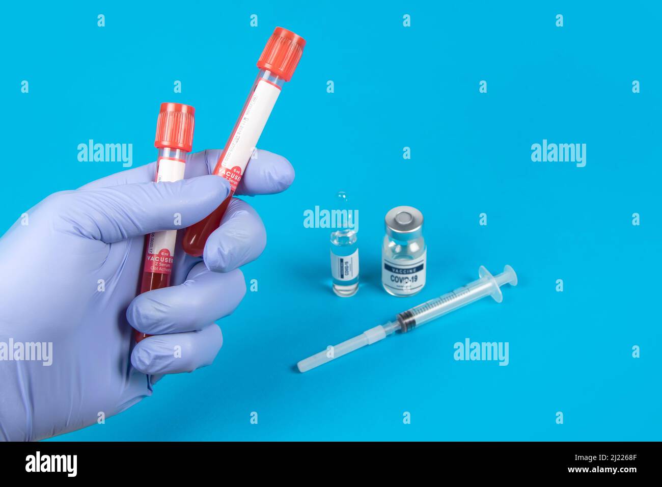 Mano di un medico che tiene un flacone di campione di sangue. Sfondo blu Foto Stock