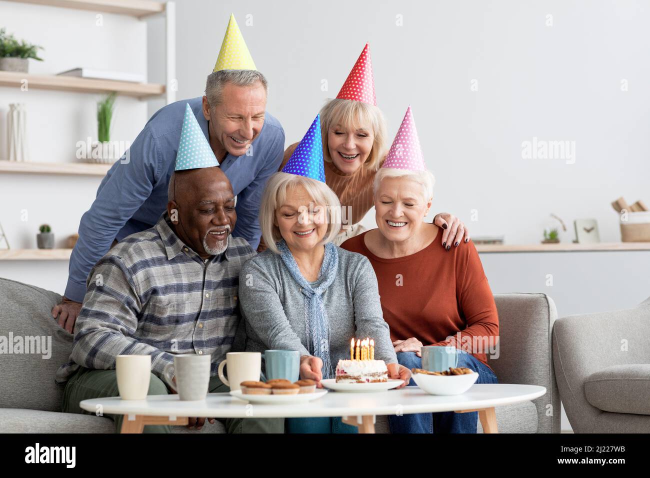 Felice gruppo multirazziale di pensionati che festeggia insieme il compleanno Foto Stock