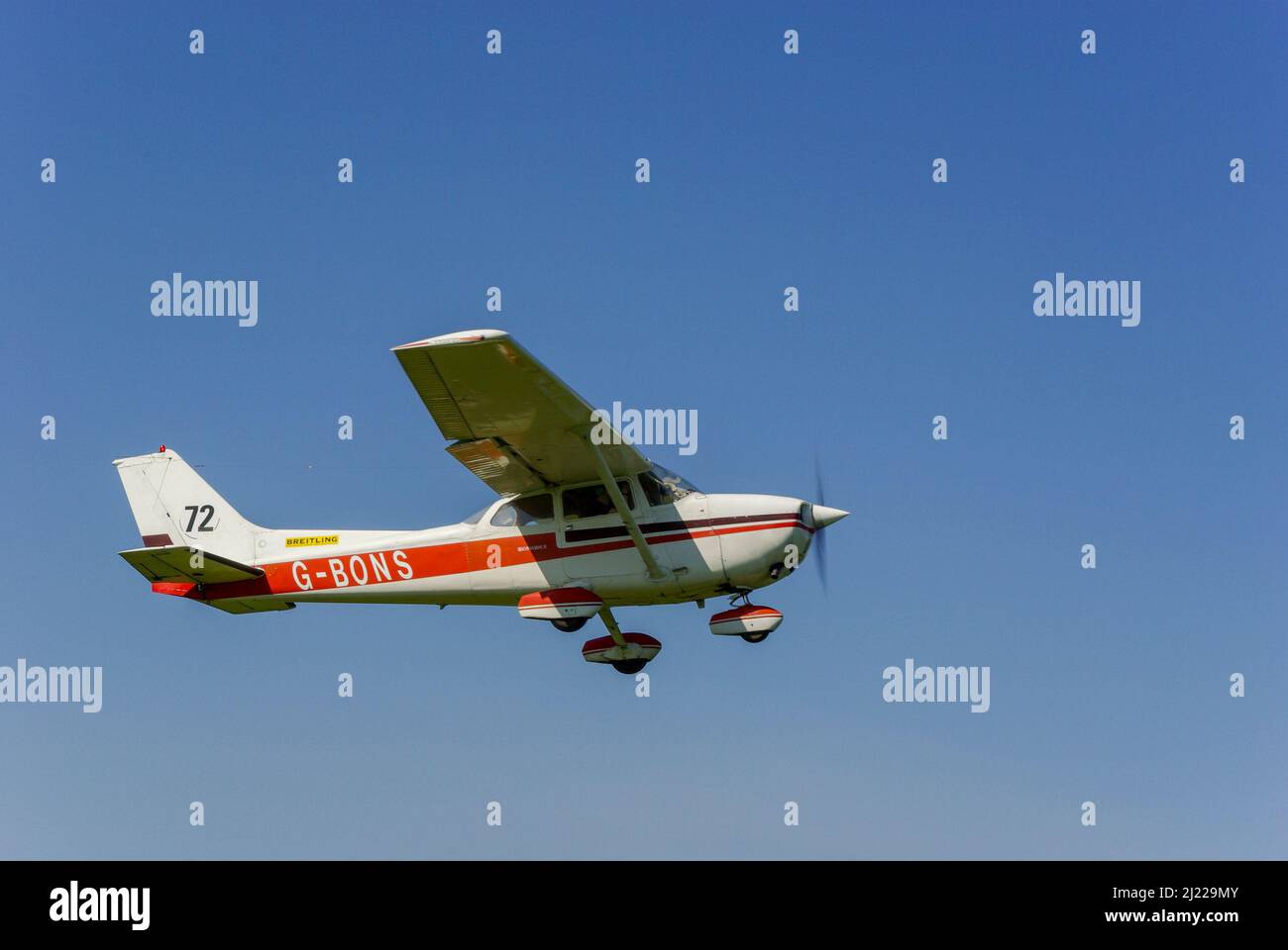 Cessna 172N Skyhawk 100 II aereo G-BONS che vola in cielo azzurro chiaro sopra il campo aereo di Great Oakley, Essex, Regno Unito. Con RAeC numero di gara in coda durante la gara Foto Stock