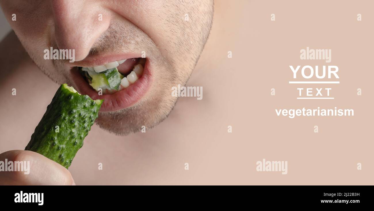 Veretarismo. Un uomo morde un cetriolo. Foto di un vegetariano che mordicchiava un cetriolo Foto Stock