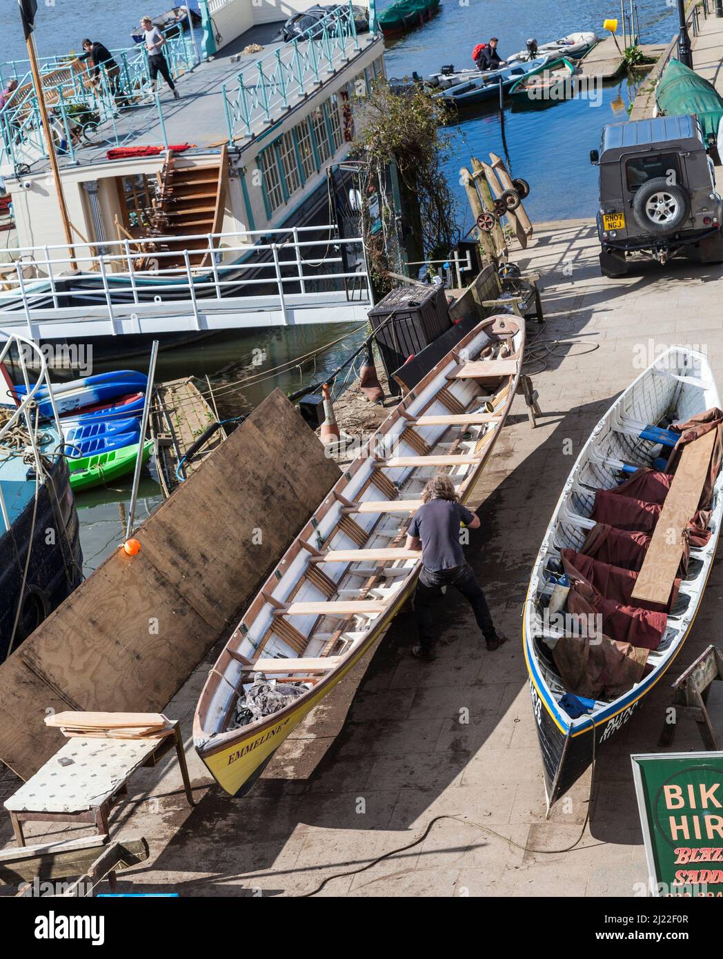 Un uomo che lavora ad una riparazione della barca sul lungofiume a Richmond upon Thames, Surrey, Inghilterra, Regno Unito Foto Stock