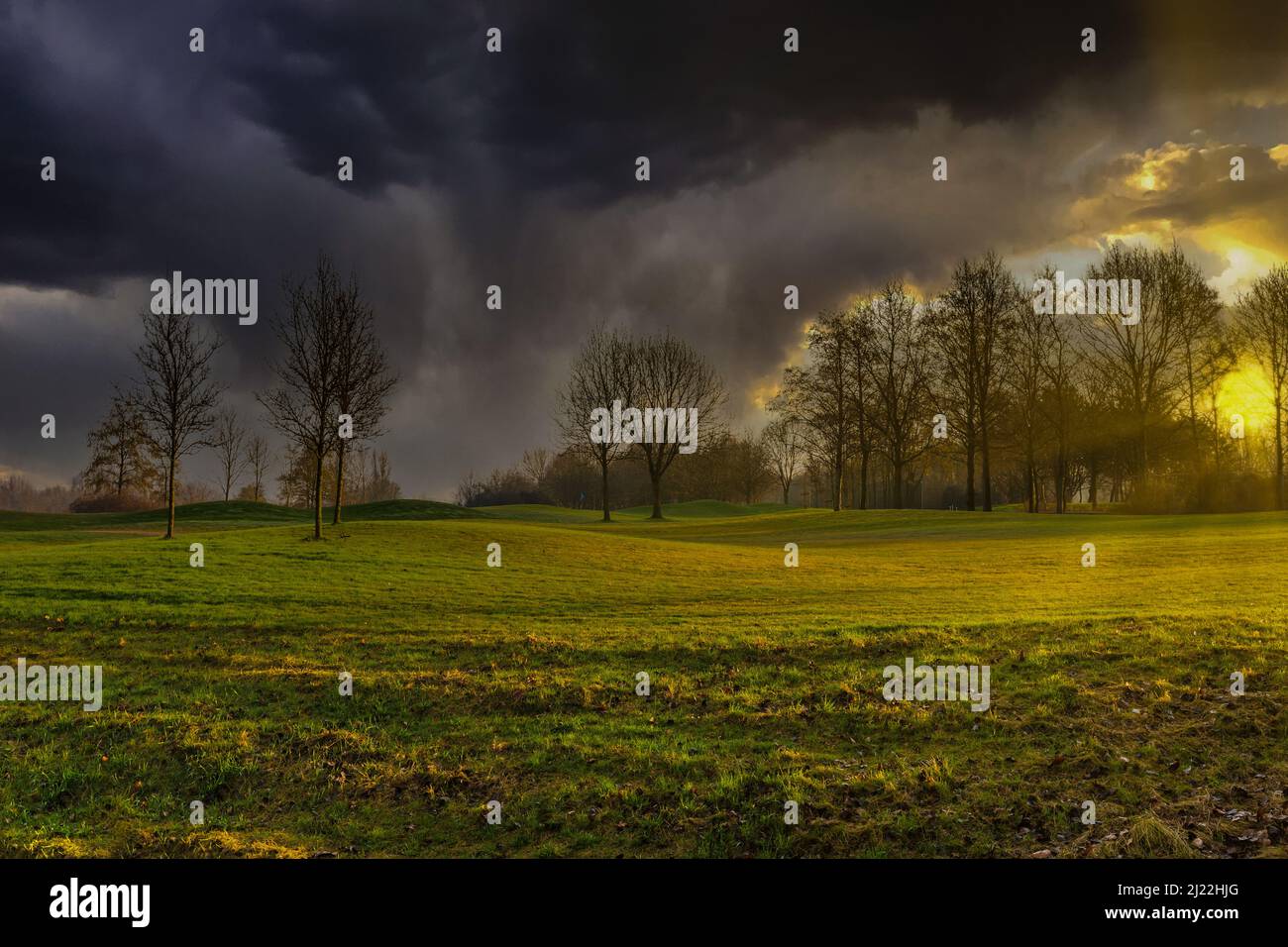 Paesaggio con nuvole pesanti e una tempesta imminente con un sole luminoso e un proiettore retroilluminato sui prati collinari di un campo da golf a Zegersloot Alphen Foto Stock