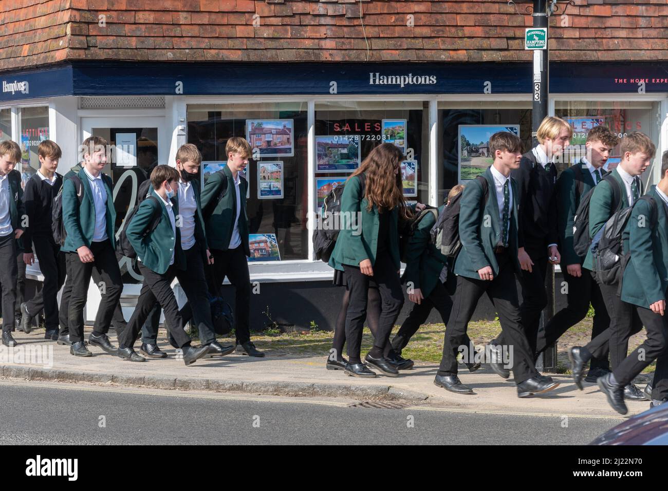 Scuola secondaria bambini alunni studenti che camminano a casa dopo la scuola attraverso il centro di Liphook, Hampshire, Inghilterra, Regno Unito Foto Stock