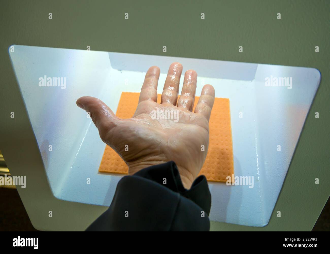 Trattamento delle mani con un antisettico in un igienizzatore automatico senza contatto Foto Stock