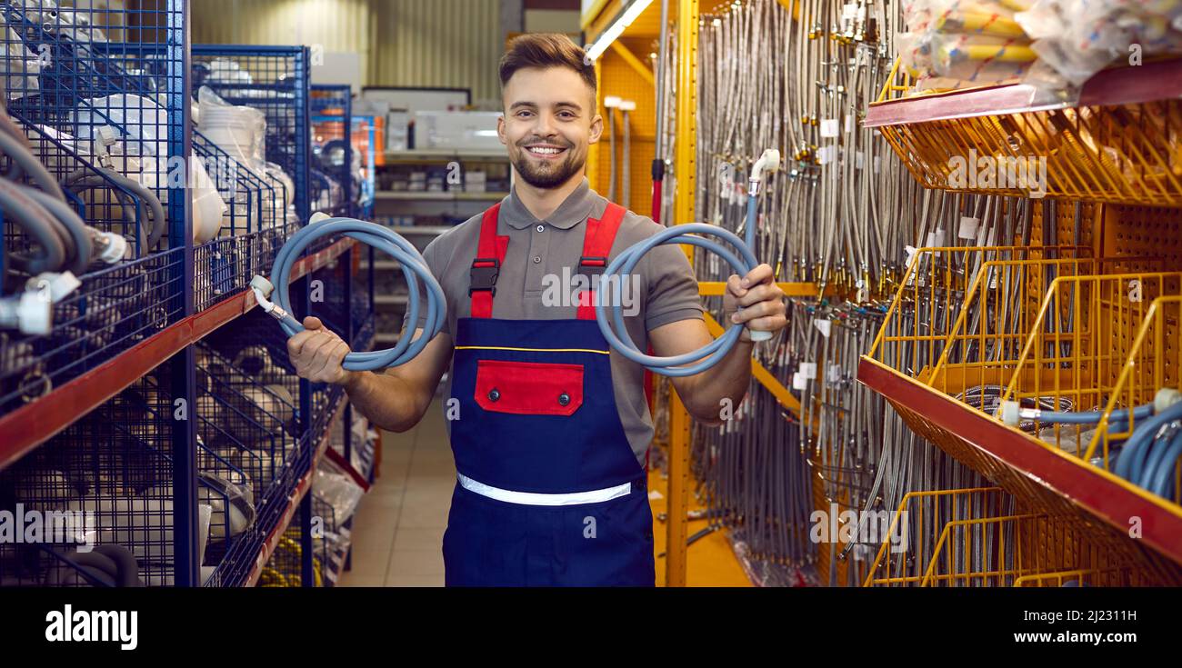 Ritratto di venditore felice al negozio DIY in piedi nel corridoio, tenendo manichette e sorridendo Foto Stock