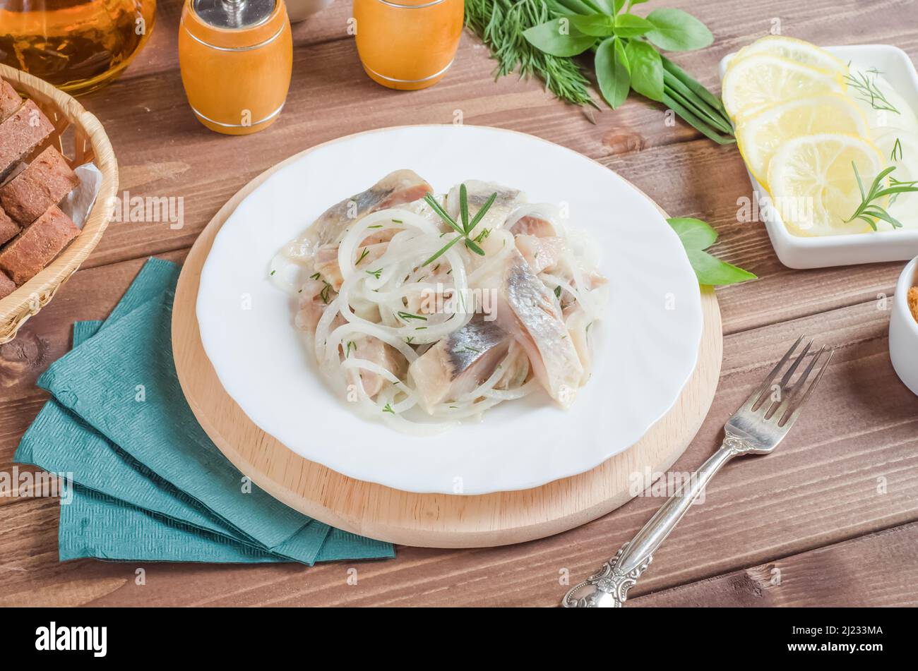 Aringa di pesce fresco con cipolla e aneto su un piatto bianco su sfondo di legno scuro Foto Stock