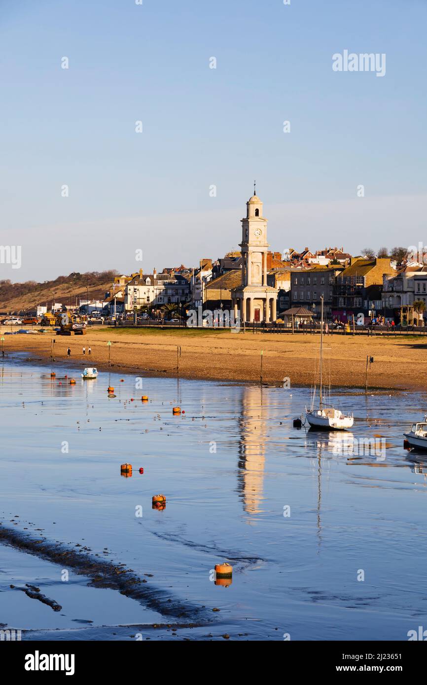 Lungomare con marea fuori. La torre dell'orologio si riflette nel mare Water.Herne Bay, Kent, Inghilterra Foto Stock