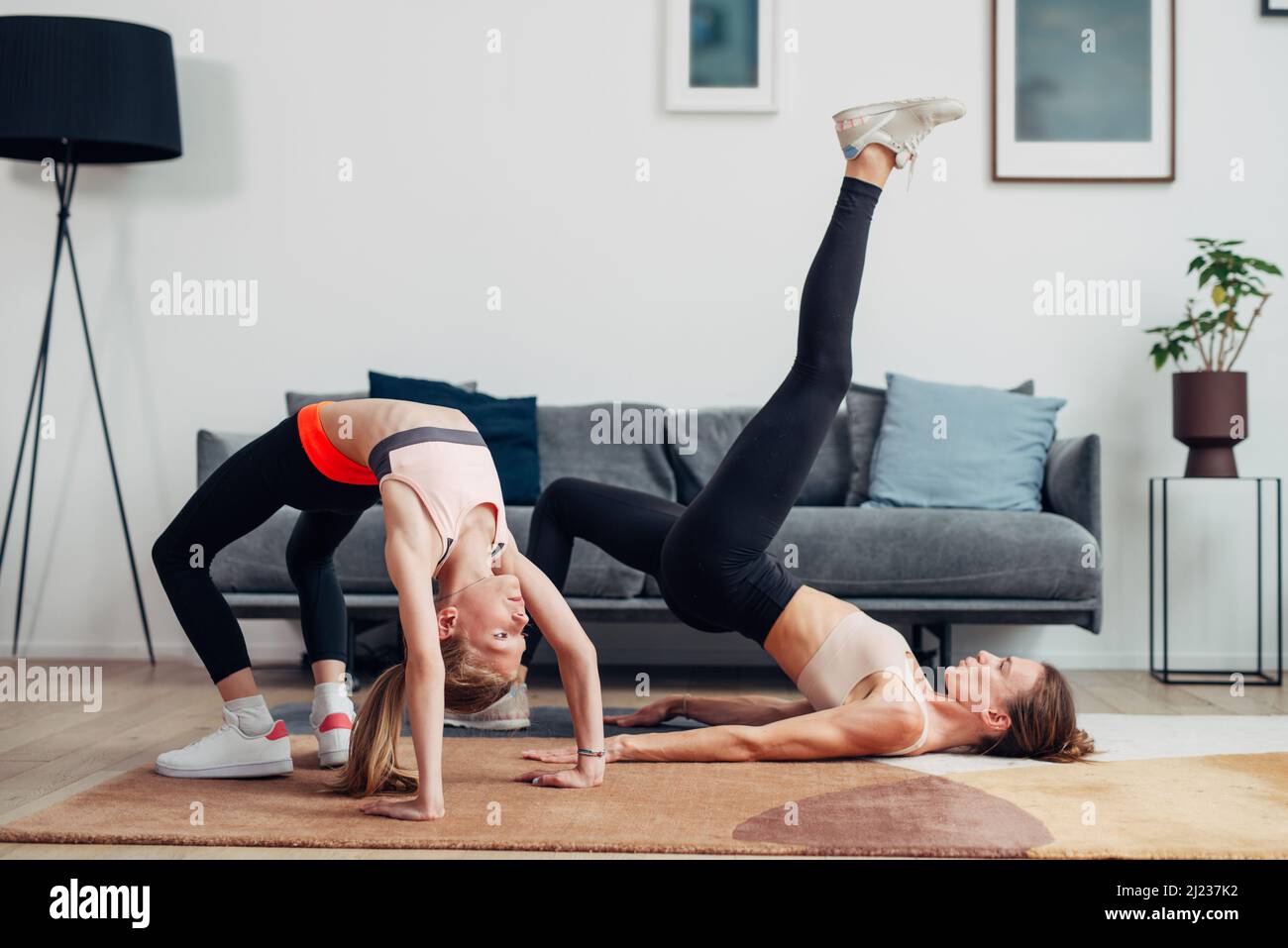 Home allenamento madre e figlia fare ponte e ponte gluteale. Foto Stock