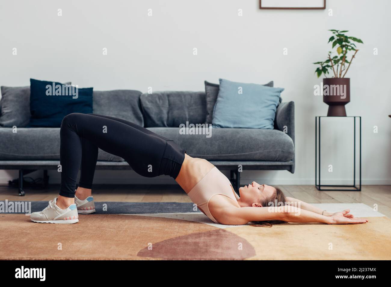Fit donna esercizi a casa facendo ponte gluteo. Foto Stock