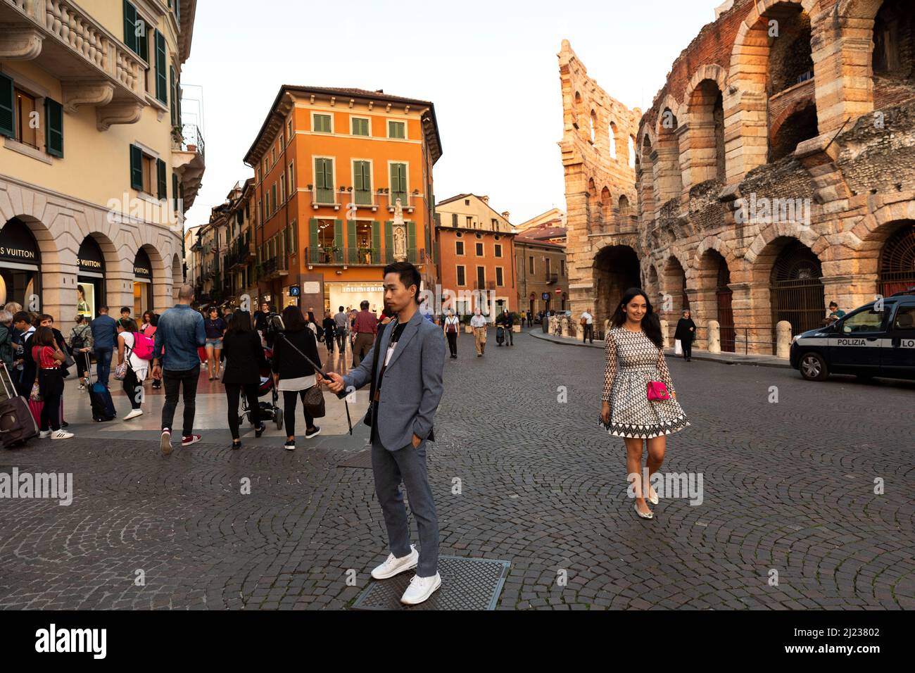 Italia,Verona, centro storico con una donna che passeggera da una persona che prende un selfie Foto Stock