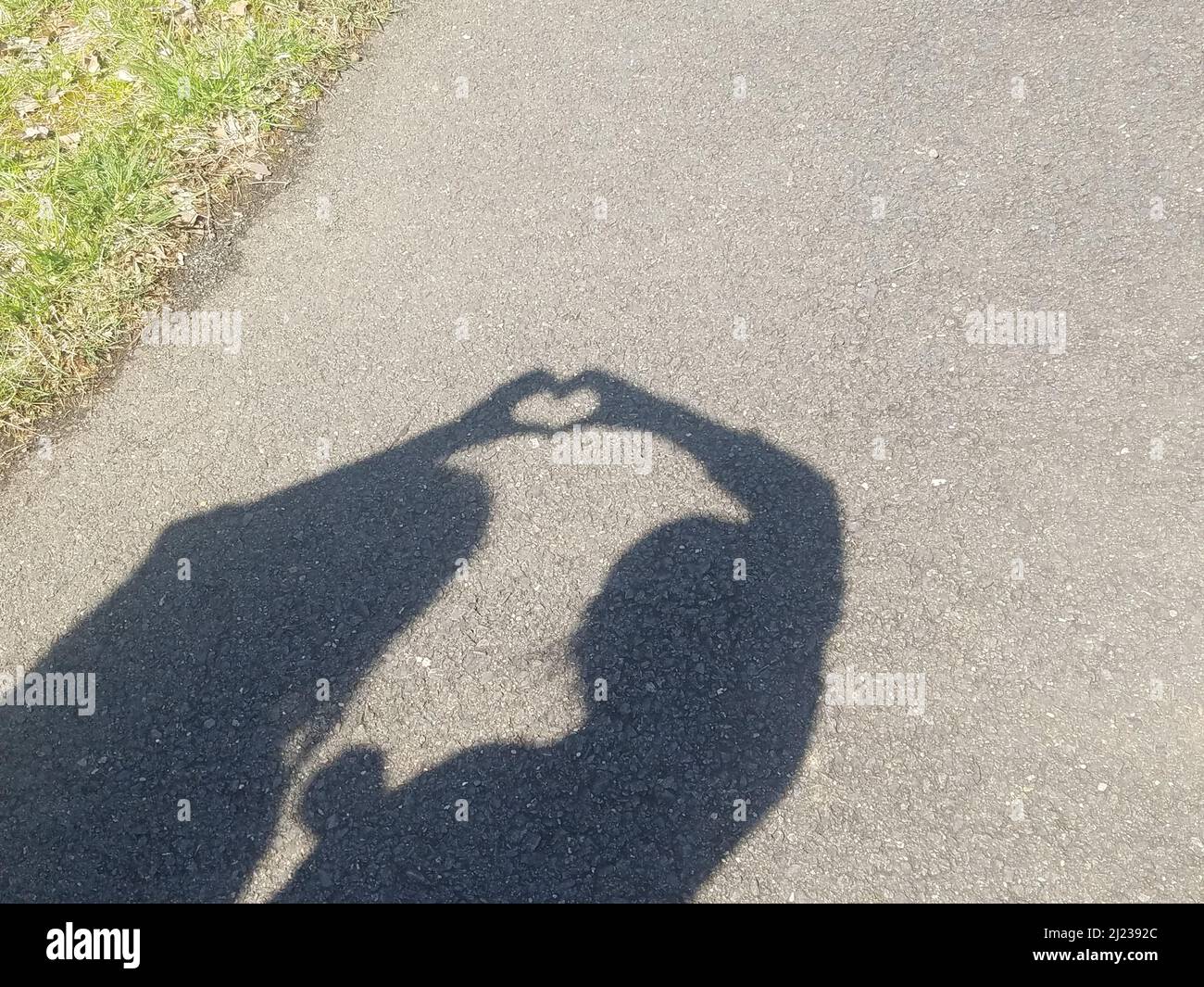 Due amici si uniscono alle mani per fare un cuore all'interno della loro ombra che significa la loro amicizia e connessione Foto Stock