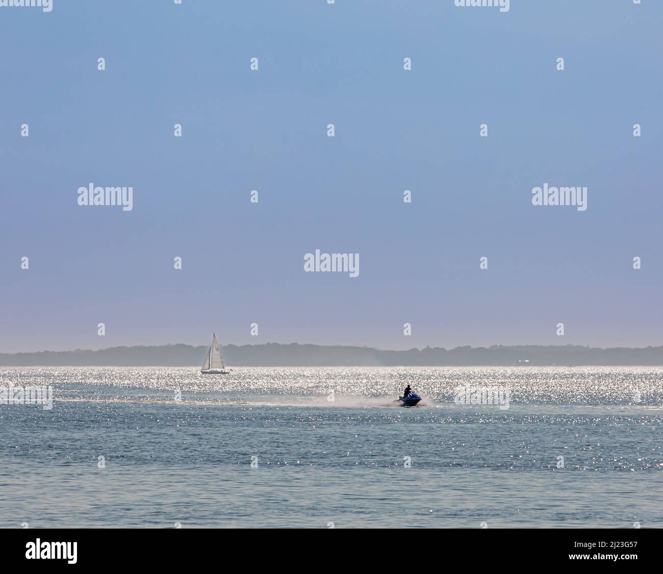 Moto d'acqua e una barca a vela al largo della costa del North Fork, NY Foto Stock