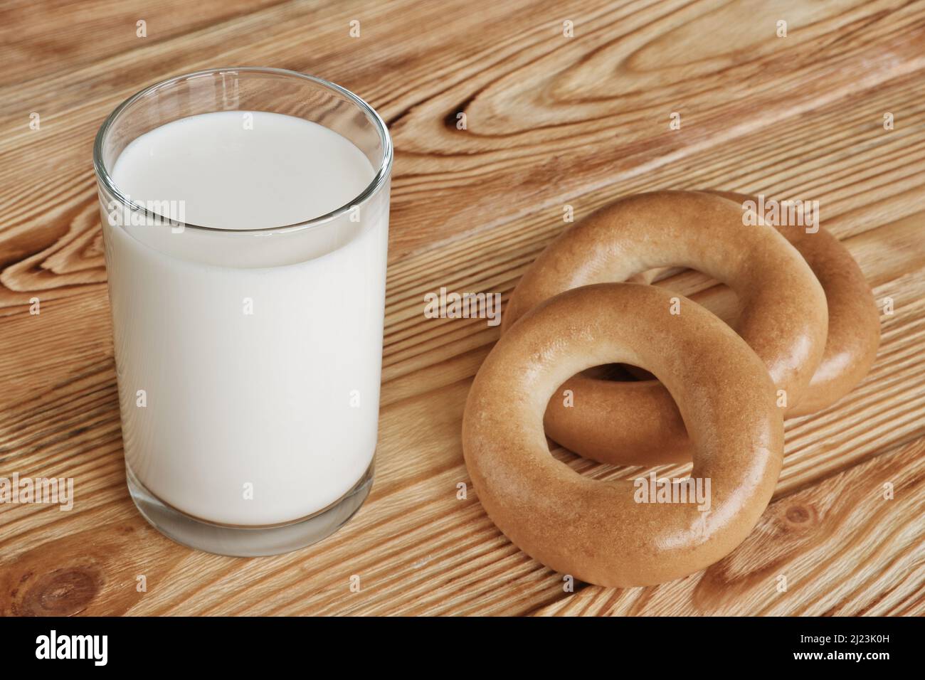 Bicchiere di latte fresco e tre bagel su un tavolo di legno. Foto Stock