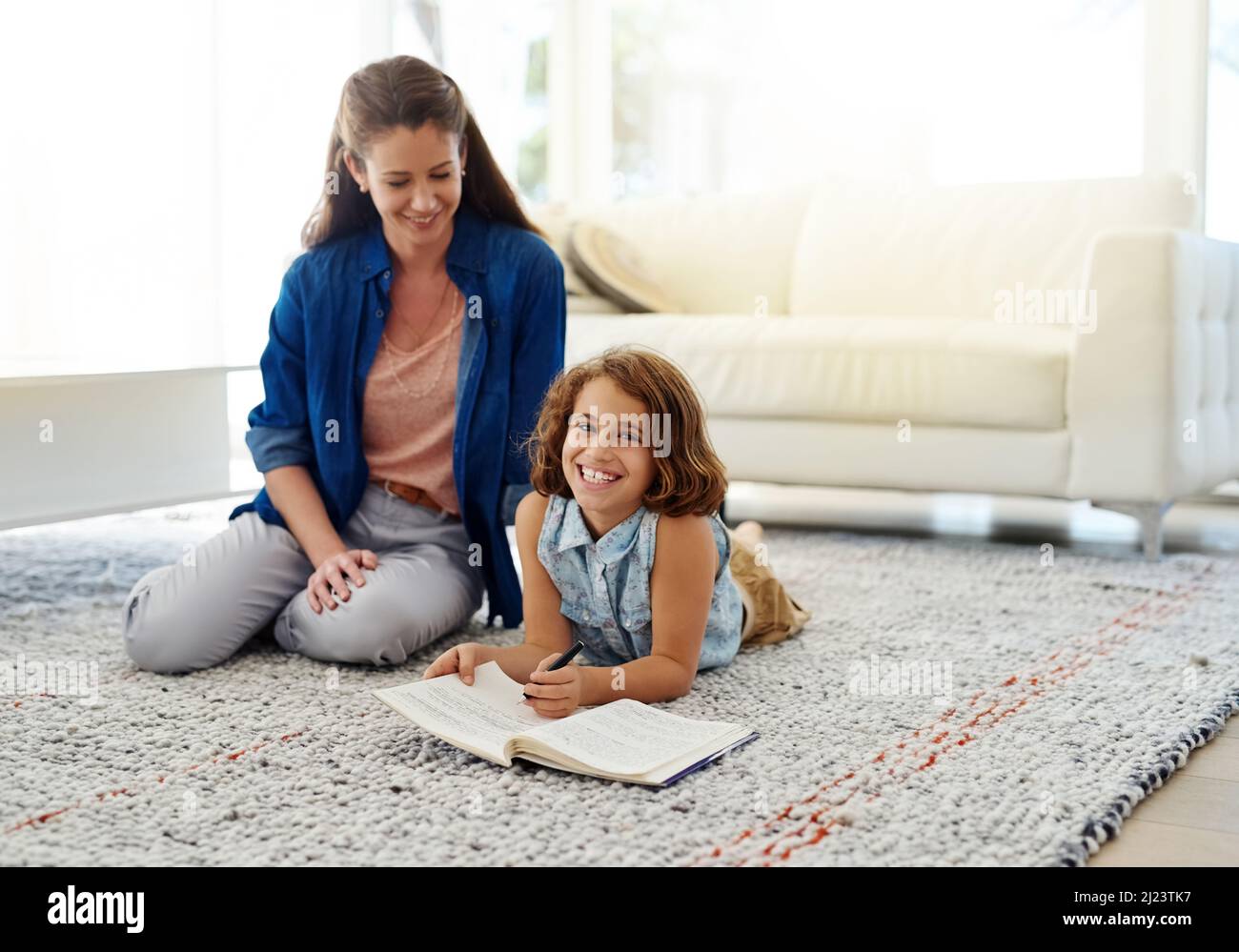 Il suo lavoro è sempre tenuto pulito e ordinato. Scatto corto di una madre che aiuta sua figlia con i suoi compiti. Foto Stock