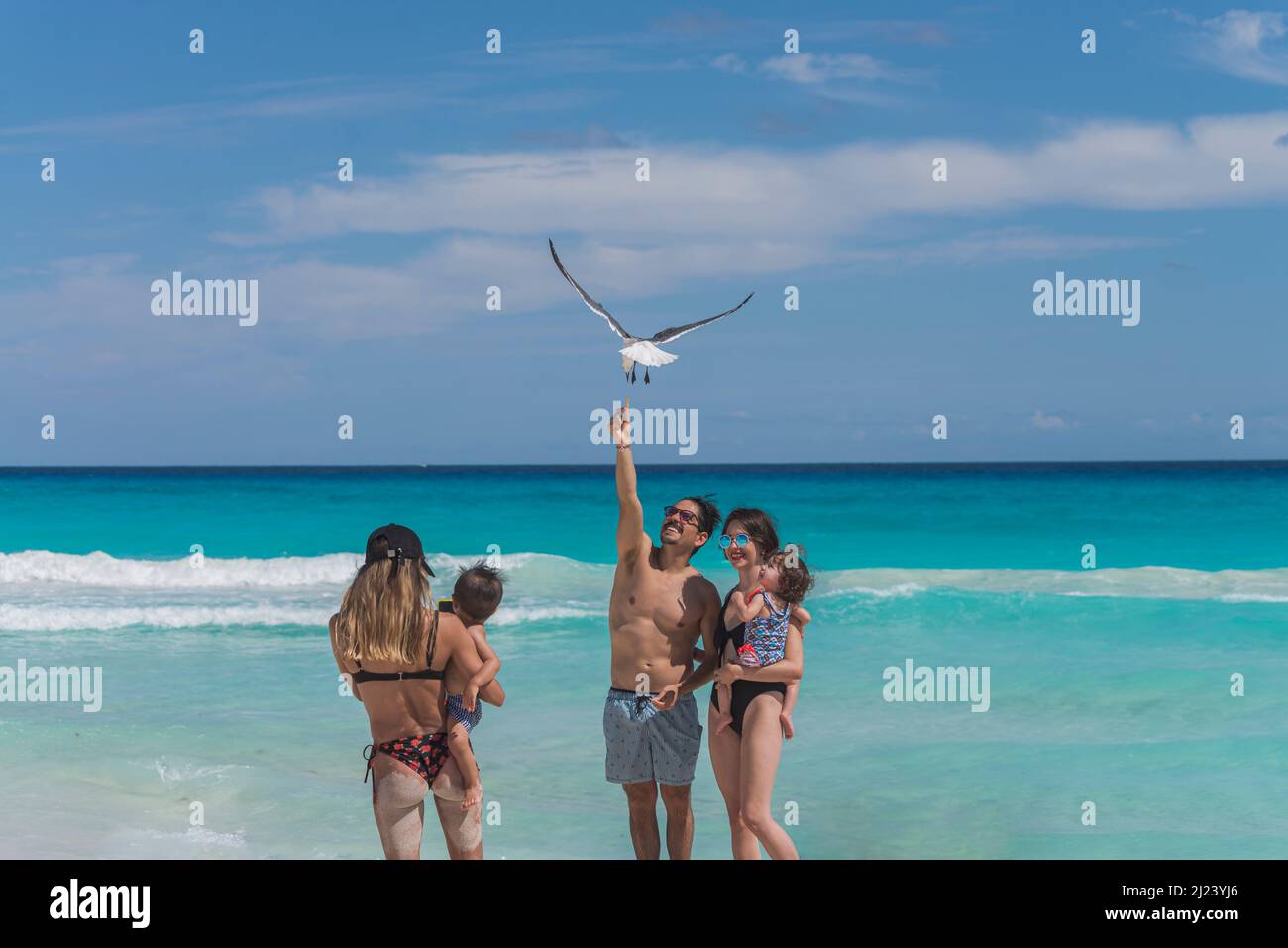 Giovane famiglia latina che cerca di nutrire i gabbiani in aria Foto Stock