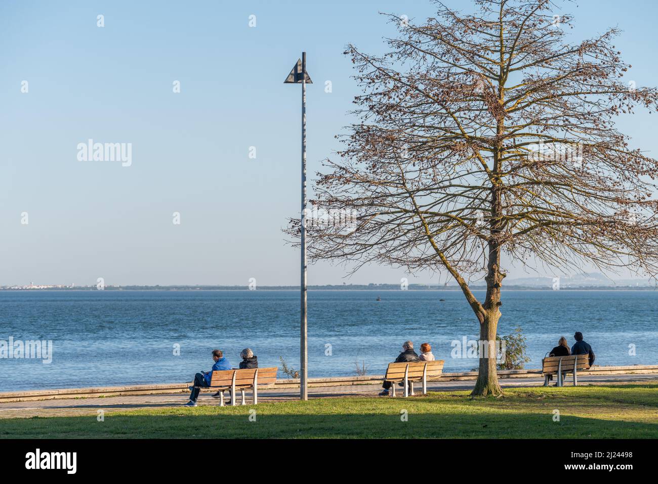 Le numerose coppie su panchine presso il fiume Tago a Lisbona, Portogallo Foto Stock
