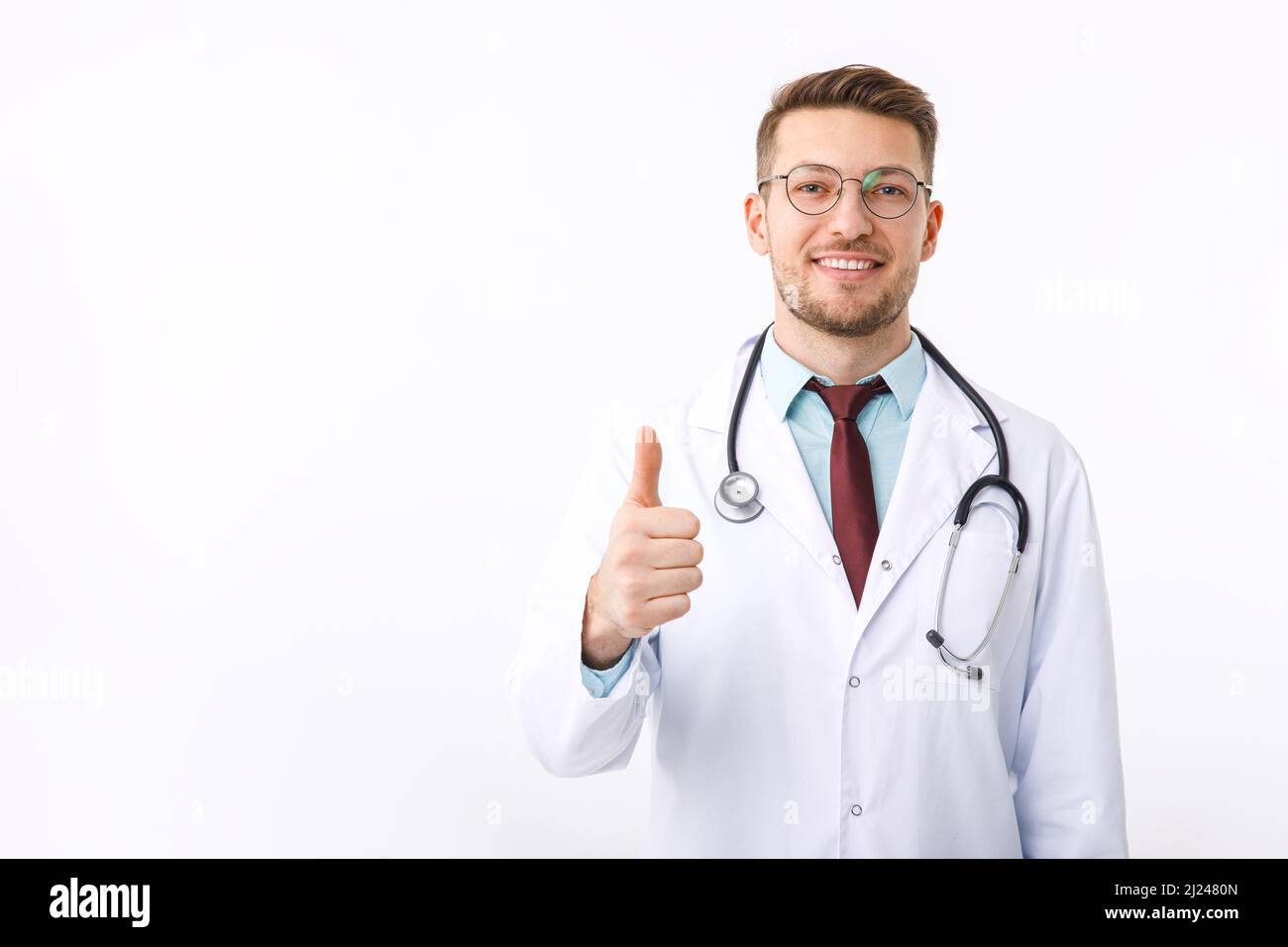 Ritratto di giovane medico fiducioso su sfondo bianco. Il medico mostra il simbolo ok Foto Stock