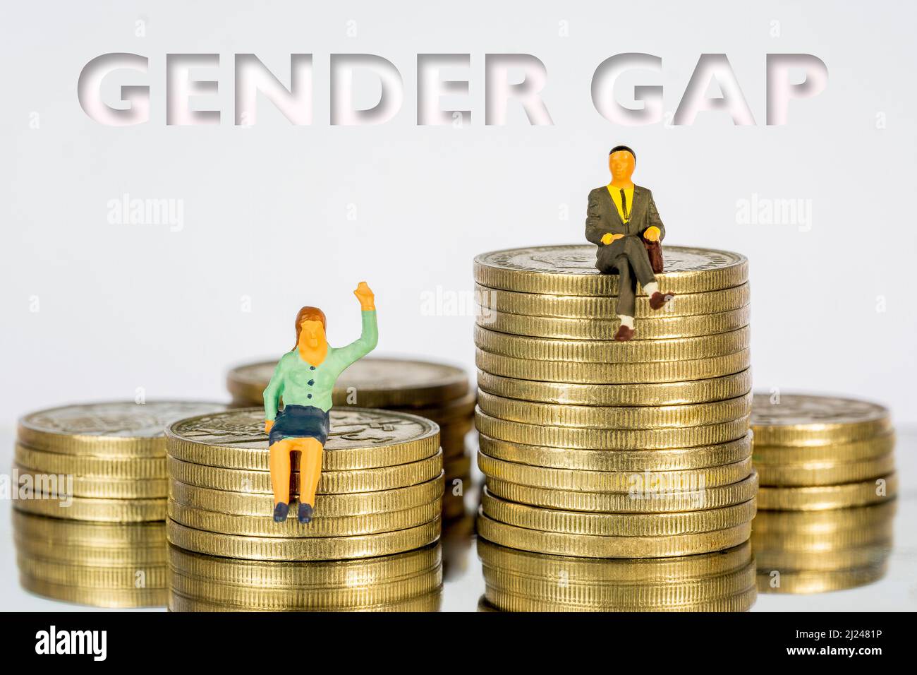 Persone in miniatura sedute su un mucchio di monete. Il concetto di distribuzione del reddito divario di genere Foto Stock