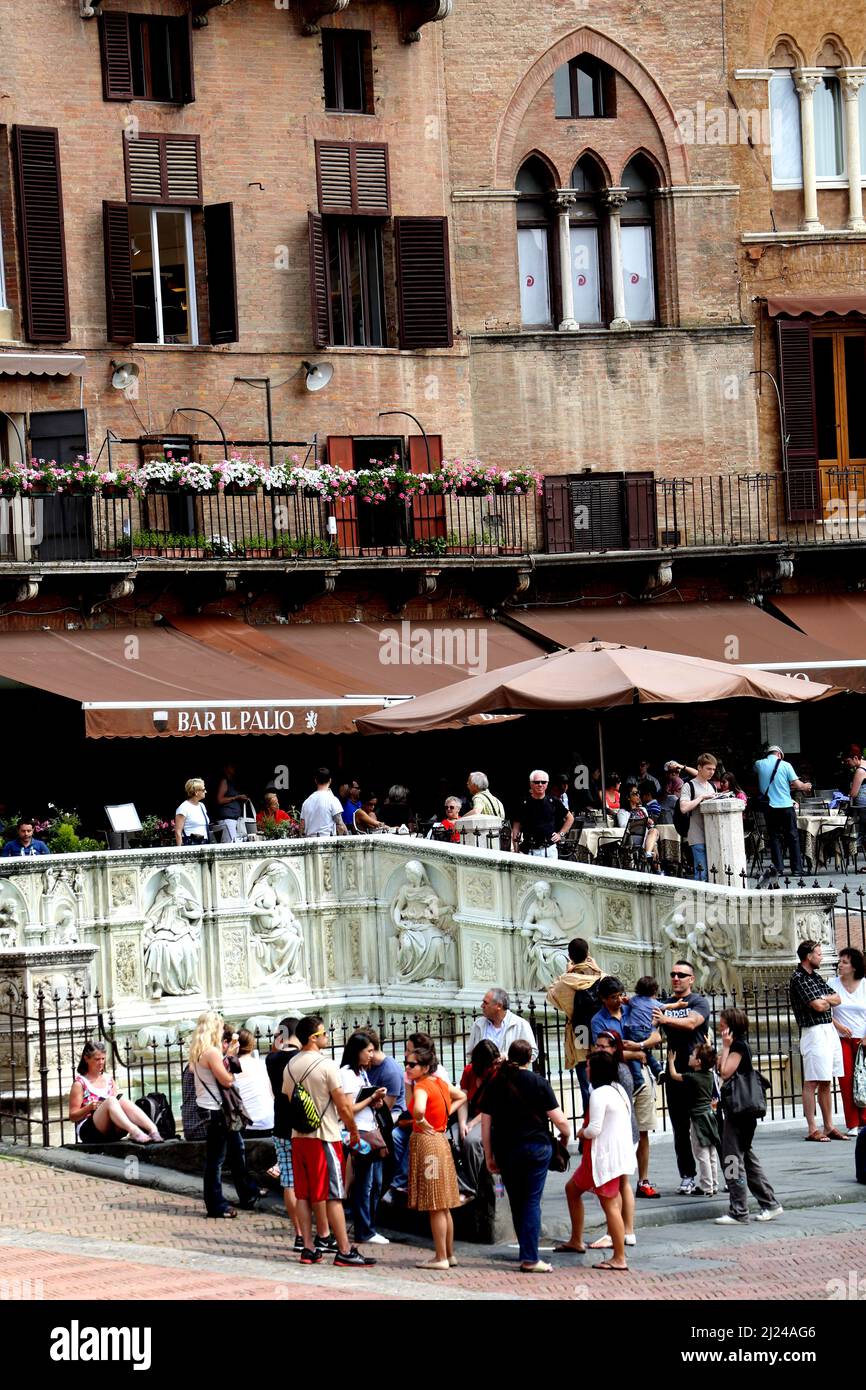 I turisti si sono riuniti intorno alla Fonte Gaia in Piazza del Campo a Siena Italia Foto Stock