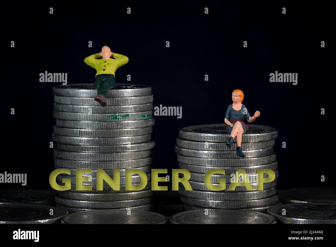 Persone in miniatura sedute su un mucchio di monete. Il concetto di distribuzione del reddito divario di genere Foto Stock