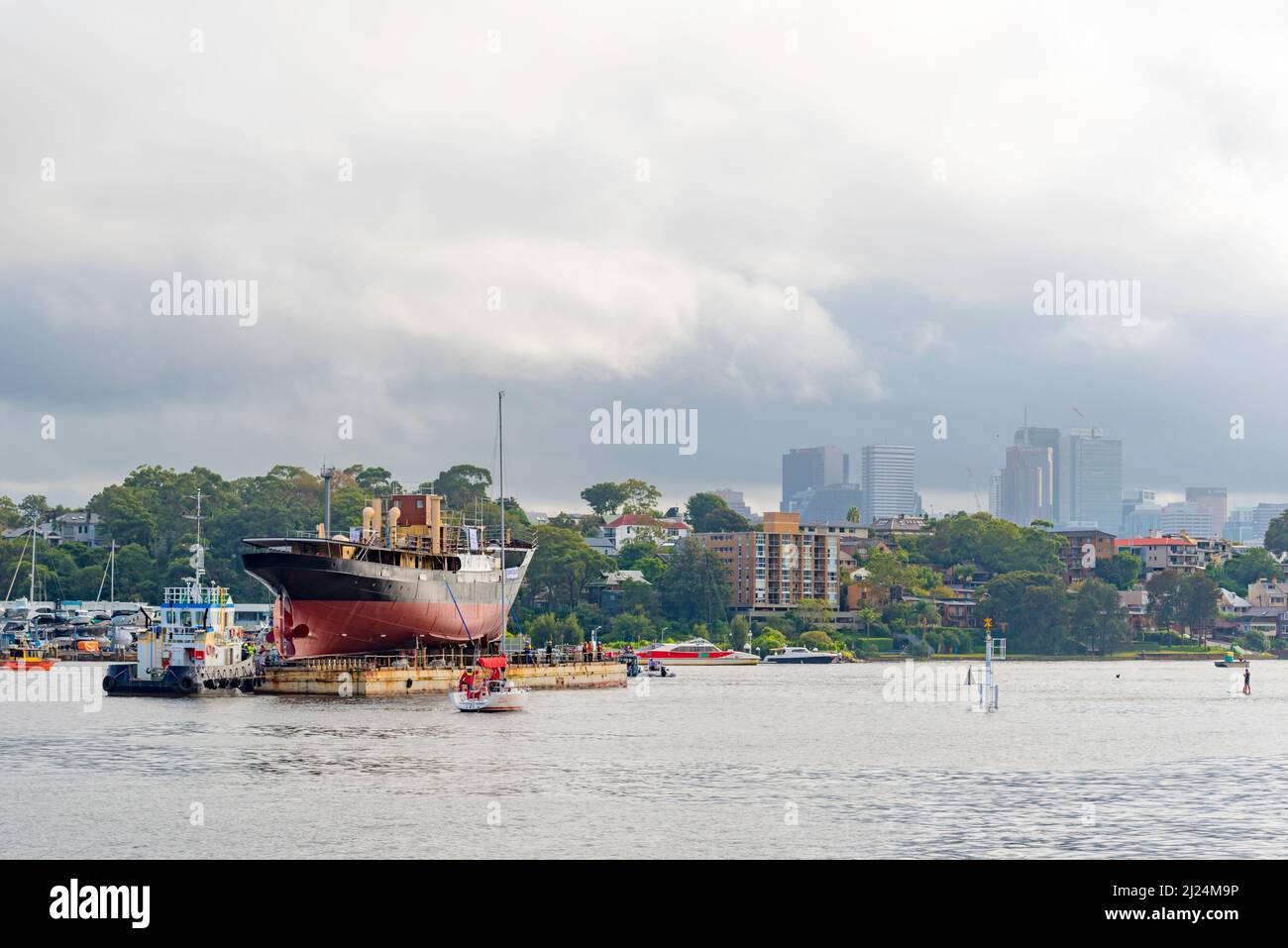 30 marzo 2022, White Bay, Sydney, Australia: La nave a vapore costiera del 1927, John Oxley che ha subito anni di restauro e conservazione, è qui raffigurata muovendosi attraverso White Bay sulla sua strada per essere finalmente rifocillata dopo 21 anni montato su un pontile presso i laboratori della Sydney Heritage Fleet a Roselle Bay. Il pontile sarà trainato lentamente verso un molo asciutto a Garden Island nel porto di Sydney, dove sarà accuratamente ripulito e testato. Foto Stock