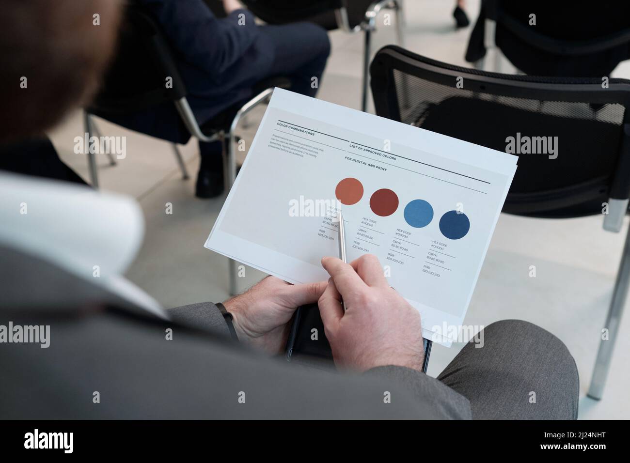 Le mani del giovane uomo d'affari che punta al cerchio beige nel documento finanziario mentre analizzano le informazioni durante la formazione Foto Stock