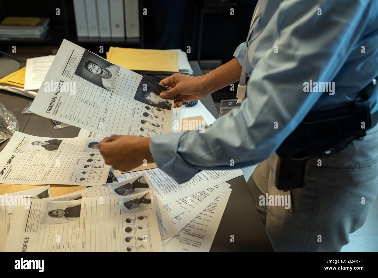 Giovane investigatore contemporaneo che detiene il profilo criminale del leader della banda sul posto di lavoro, mentre imparano le sue informazioni personali Foto Stock