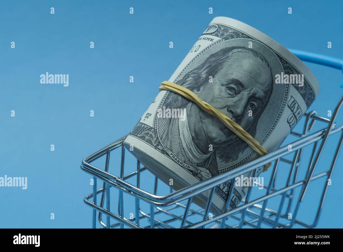 Dollari arrotolati in un tubo giacciono in un cestino di alimentari. Foto Stock