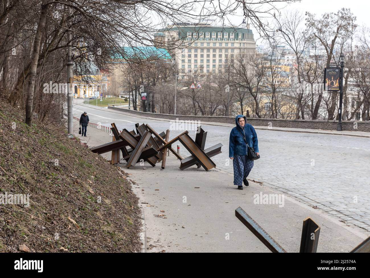 Kiev, Ucraina. 26th Mar 2022. Una donna che indossa una giacca passa accanto a un hedgehog in una strada vuota a Kyiv. La Russia ha invaso l'Ucraina il 24 febbraio 2022, scatenando il più grande attacco militare in Europa dalla seconda guerra mondiale Oltre 3 milioni di ucraini hanno già lasciato il paese e la storica città portuale di Odessa è sotto la minaccia di bombardamenti da parte delle forze russe. Credit: SOPA Images Limited/Alamy Live News Foto Stock