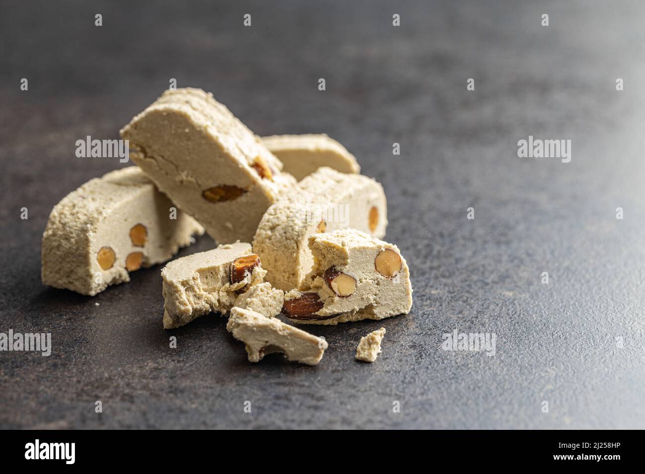Halva di tahini dolce con mandorle. Dessert turco su un tavolo da cucina. Foto Stock
