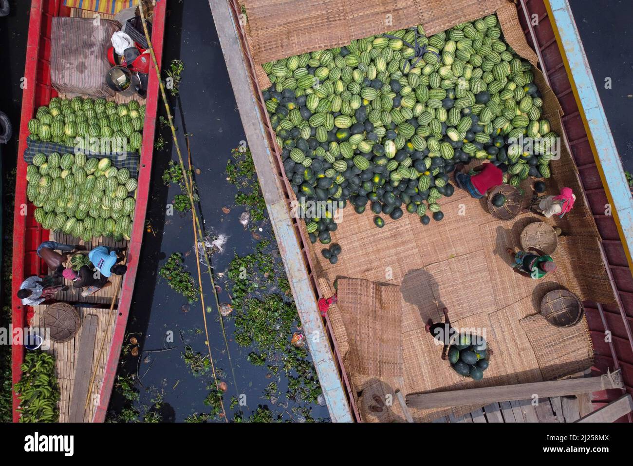 30 marzo 2022, Narayanganj, Dhaka, Bangladesh: I lavoratori scaricano i cocomeri dalle barche in un vivace mercato all'ingrosso di frutta sul fiume a Narayanganj, Bangladesh. Ogni giorno, più di 50.000 cocomeri provengono da diversi distretti di questo mercato all'ingrosso della frutta. I lavoratori trasportano grandi cesti di cocomeri dalle barche di legno prima che siano caricati nei furgoni di consegna che aspettano di trasportarli ad ogni angolo del Bangladesh. I cocomeri di buona qualità sono stati un raccolto di paraurti quest'anno a causa delle condizioni meteorologiche favorevoli e un'agricoltura migliorata. Essendo uno dei frutti più popolari durante t Foto Stock