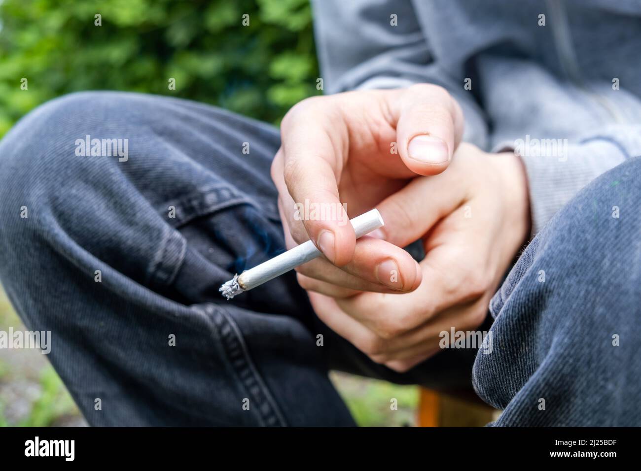 La persona tiene una sigaretta in mano al primo piano della strada Foto Stock