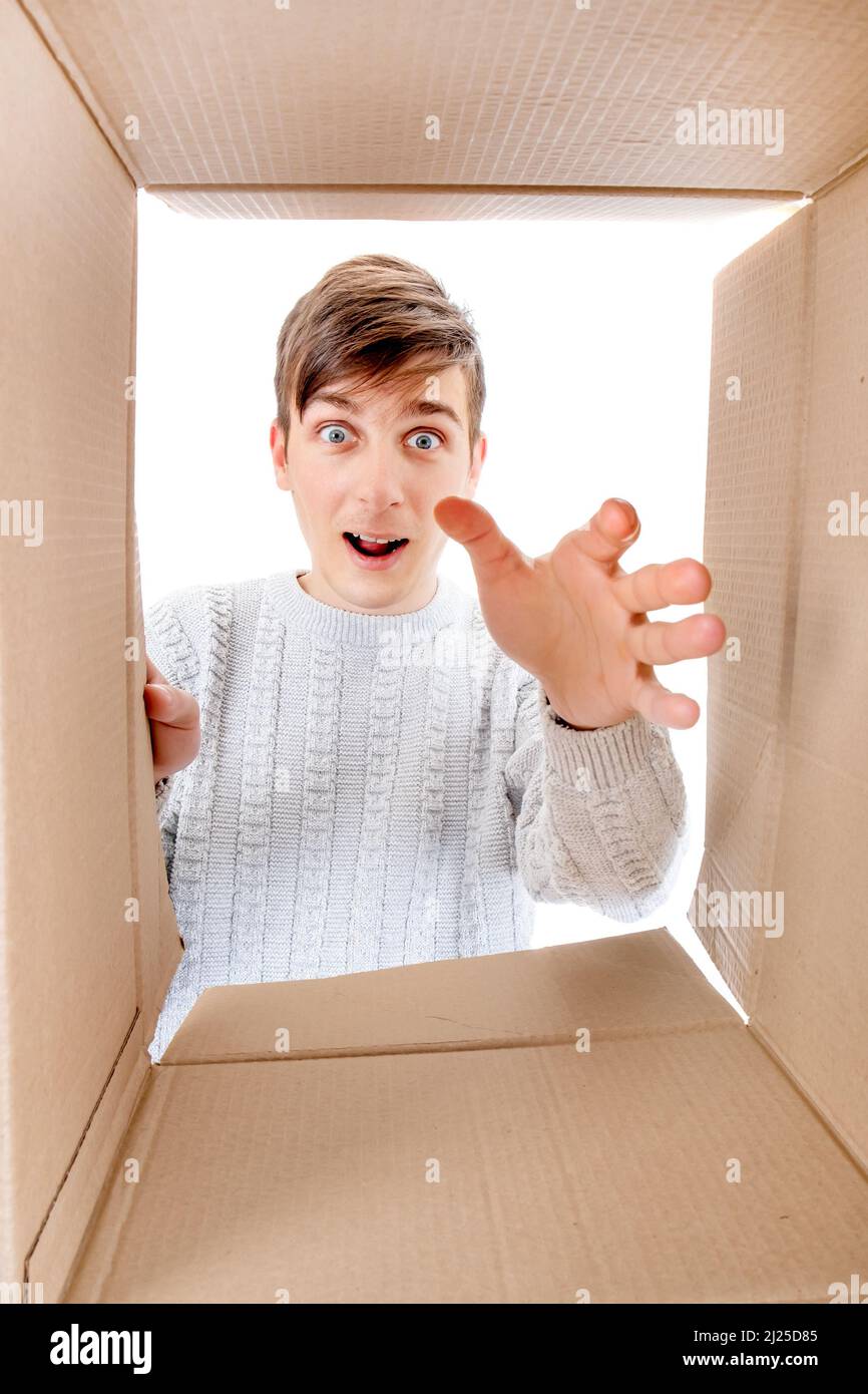 Felice e sorpreso giovane uomo guardando dentro una scatola e raggiungendo una mano Foto Stock