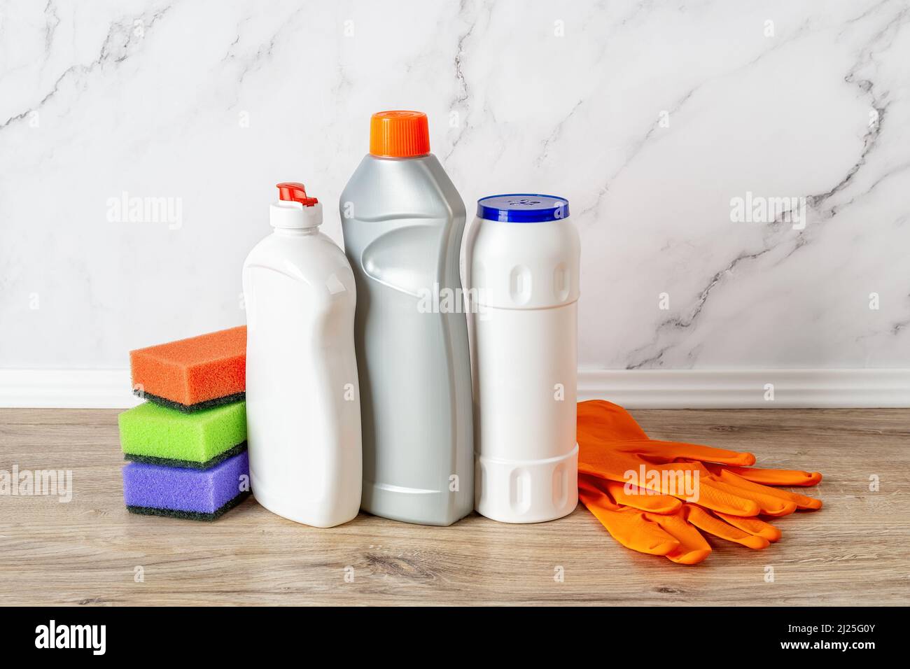 Forniture per la pulizia della cucina contro la parete di marmo. Liquido per lavastoviglie, polvere detergente, detergente per forno, spugne in schiuma e guanti di gomma. Foto Stock