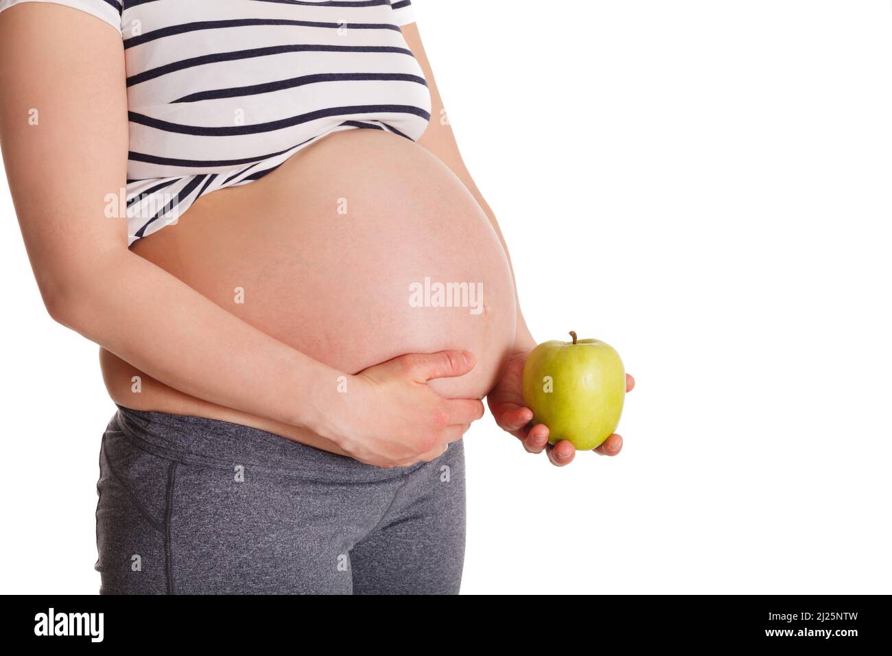 Donna incinta in piedi e tenendo la mela vicino al suo stomaco Foto Stock