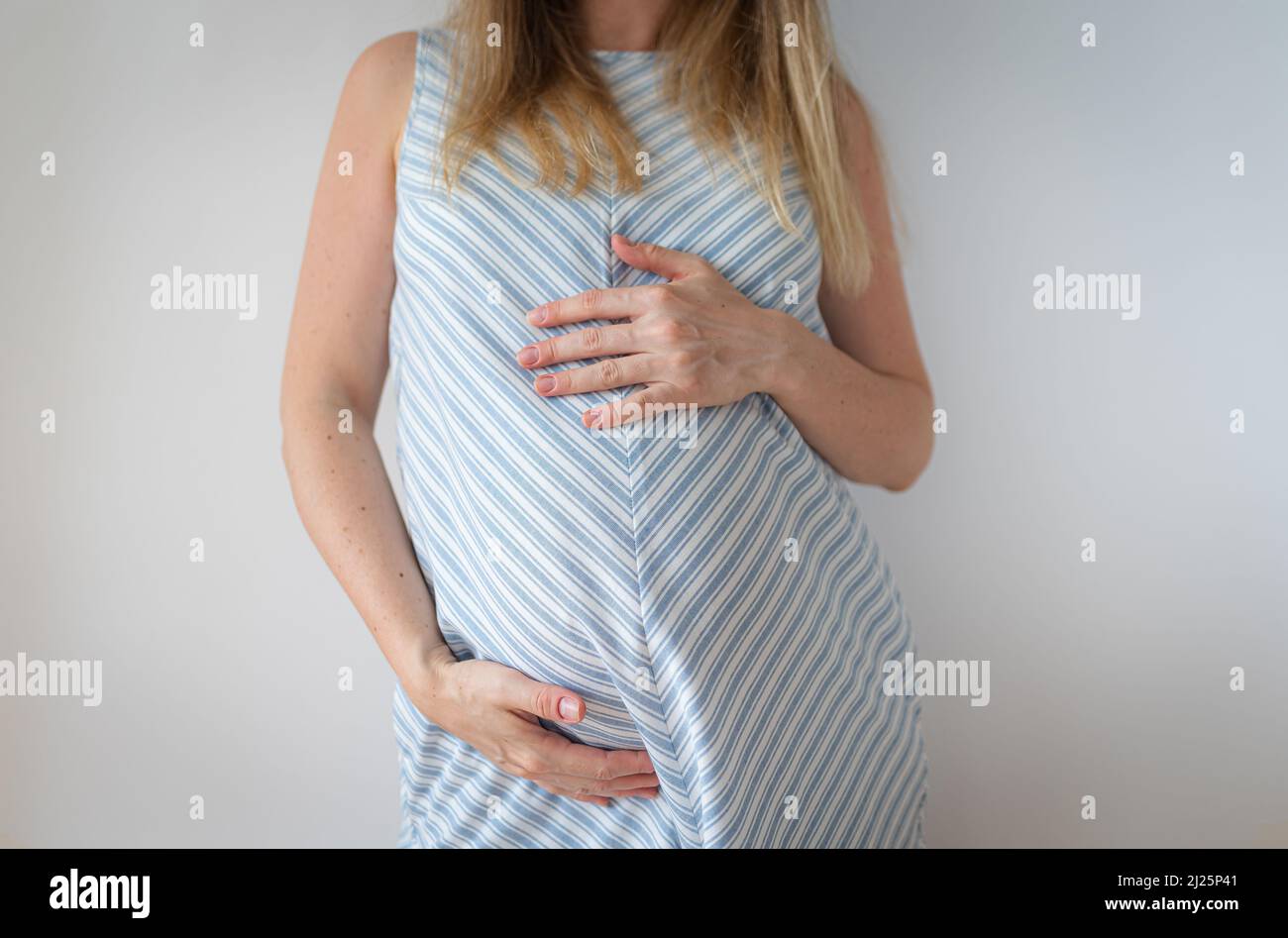 donna incinta in piedi tenendo le mani sullo stomaco Foto Stock