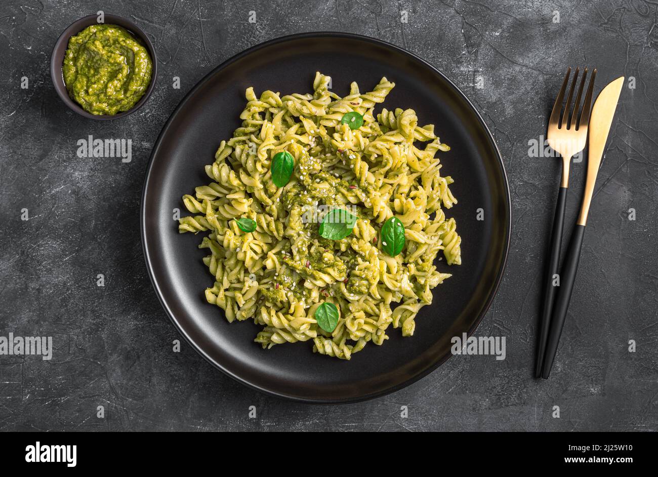 Una porzione di pasta con salsa di pesto di basilico su sfondo scuro. Foto Stock