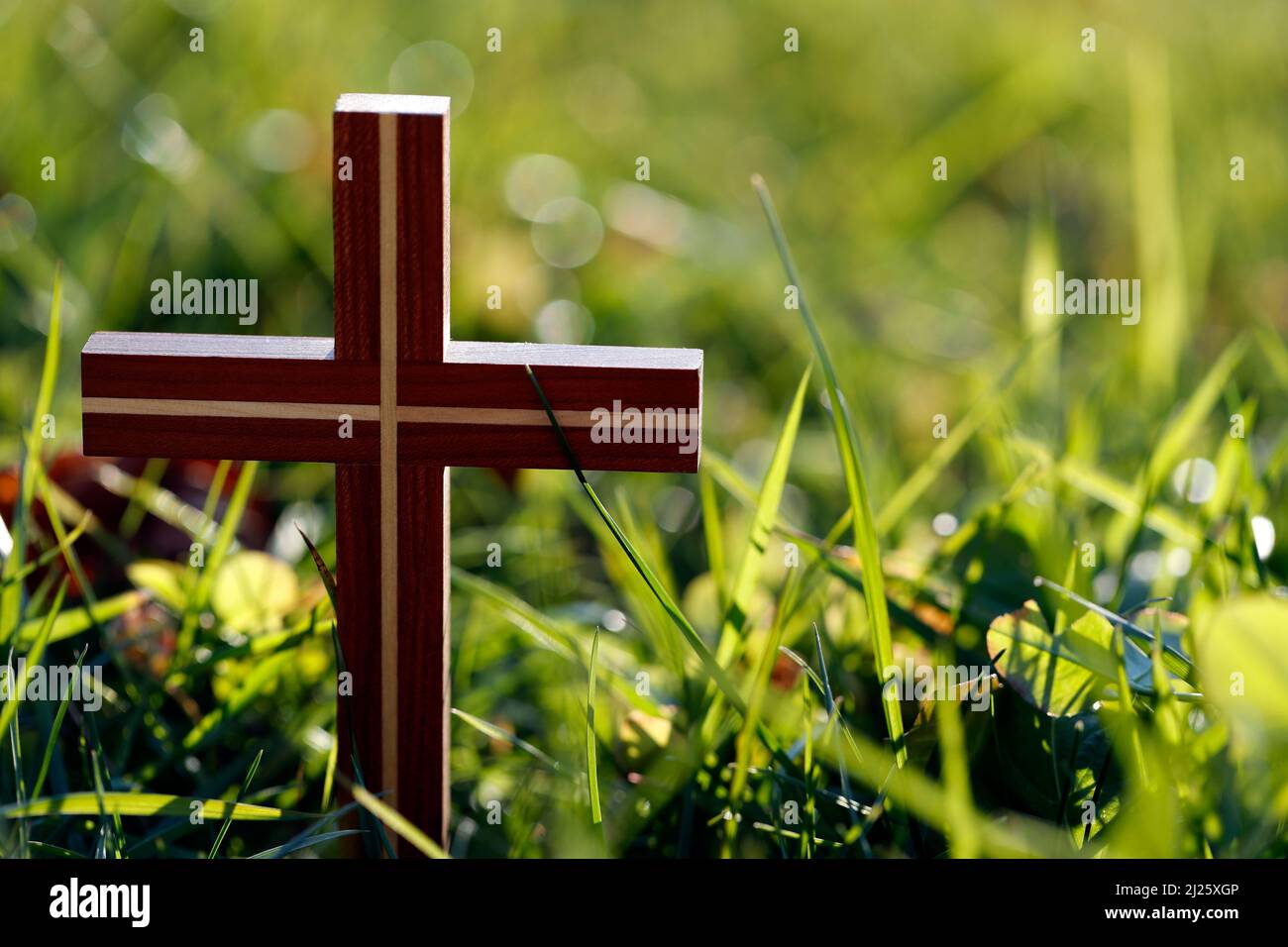 Croce cristiana su erba verde. Concetto di fede e spiritualità. Foto Stock
