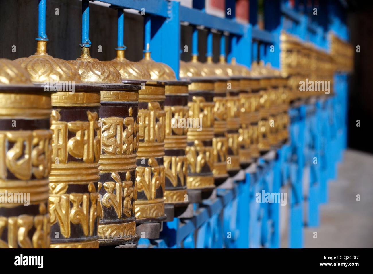 Shakhya Tharig Monastero buddista. Ruote di preghiera in metallo rotolanti cerchiate. Un mantra è scritto in lingua tibetana, all'esterno della ruota. Foto Stock
