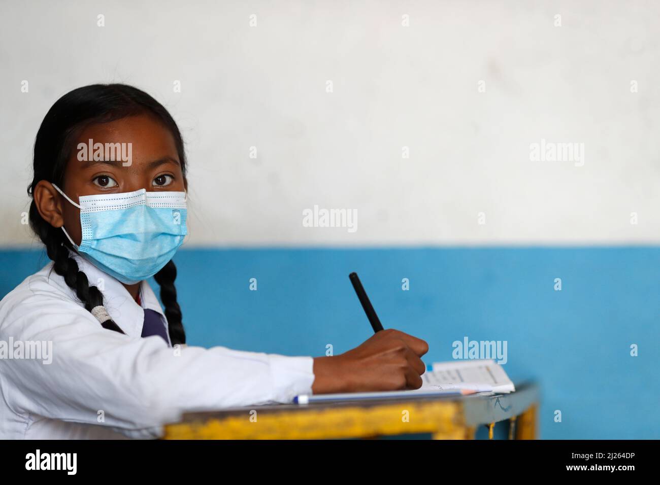 Scuola secondaria. Ragazza che indossa una maschera chirurgica in classe. Foto Stock