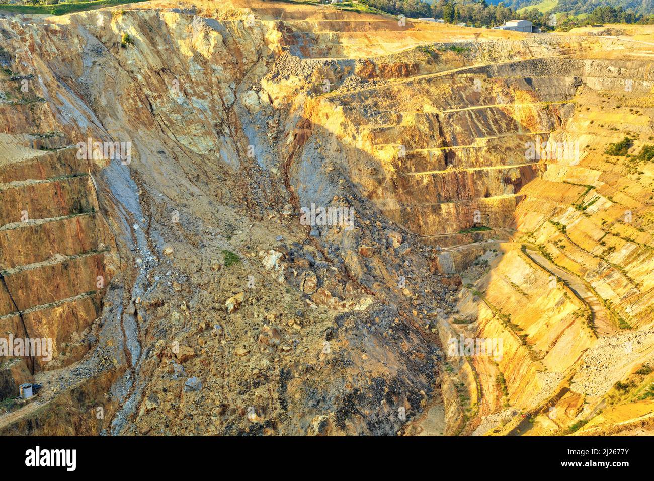 Vista su una miniera d'oro a cielo aperto, con terrazze per il trasporto di minerali. Un scivolo ha crollato un muro della buca. Martha Mine, Waihi, Nuova Zelanda Foto Stock